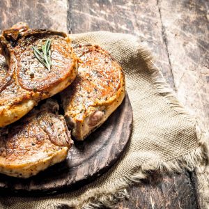 Grilled pork steak with spices. On wooden background.